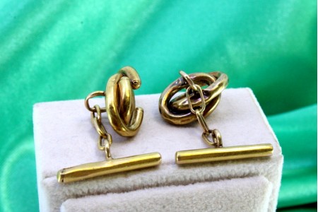 Botões de punho em ouro amarelo com enrolamentos entrelaçados em forma de elos.